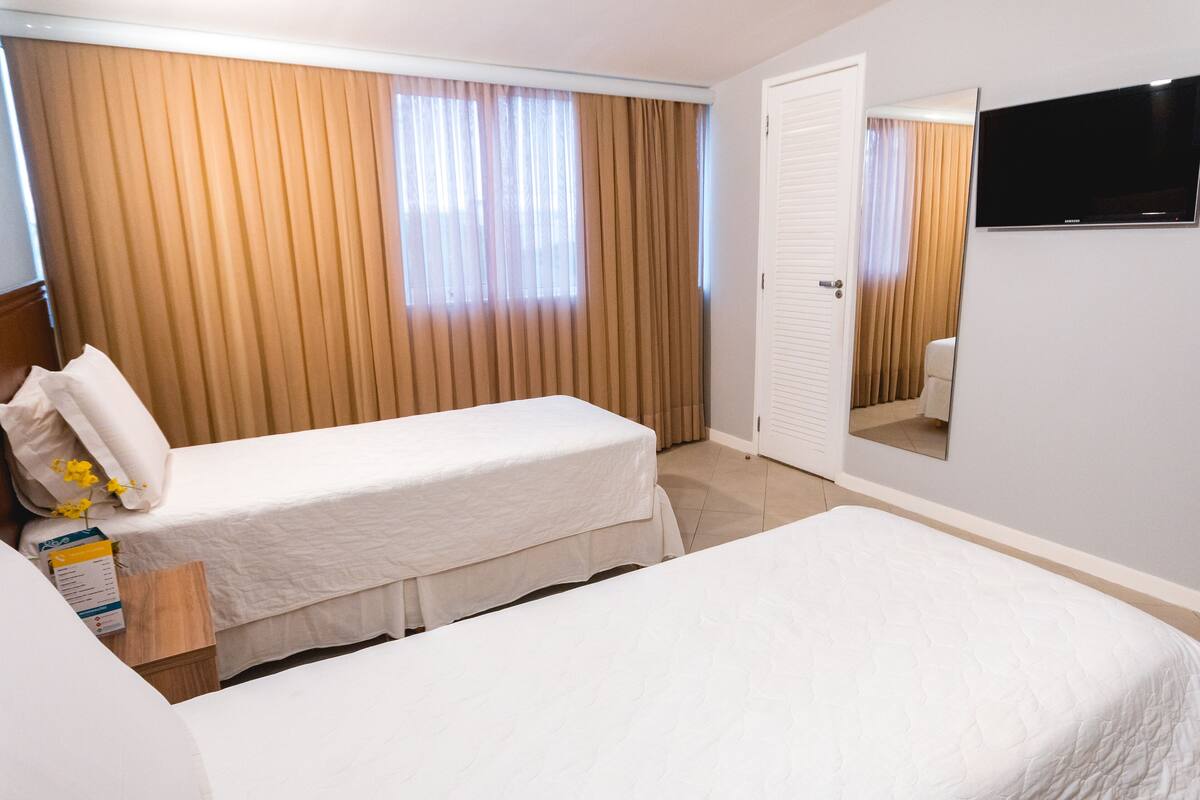 A hotel room with two beds, a television, and a door.