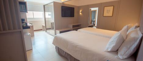 A modern hotel room with a large bed, a flat-screen TV mounted on the wall, and a glass door leading to a balcony.