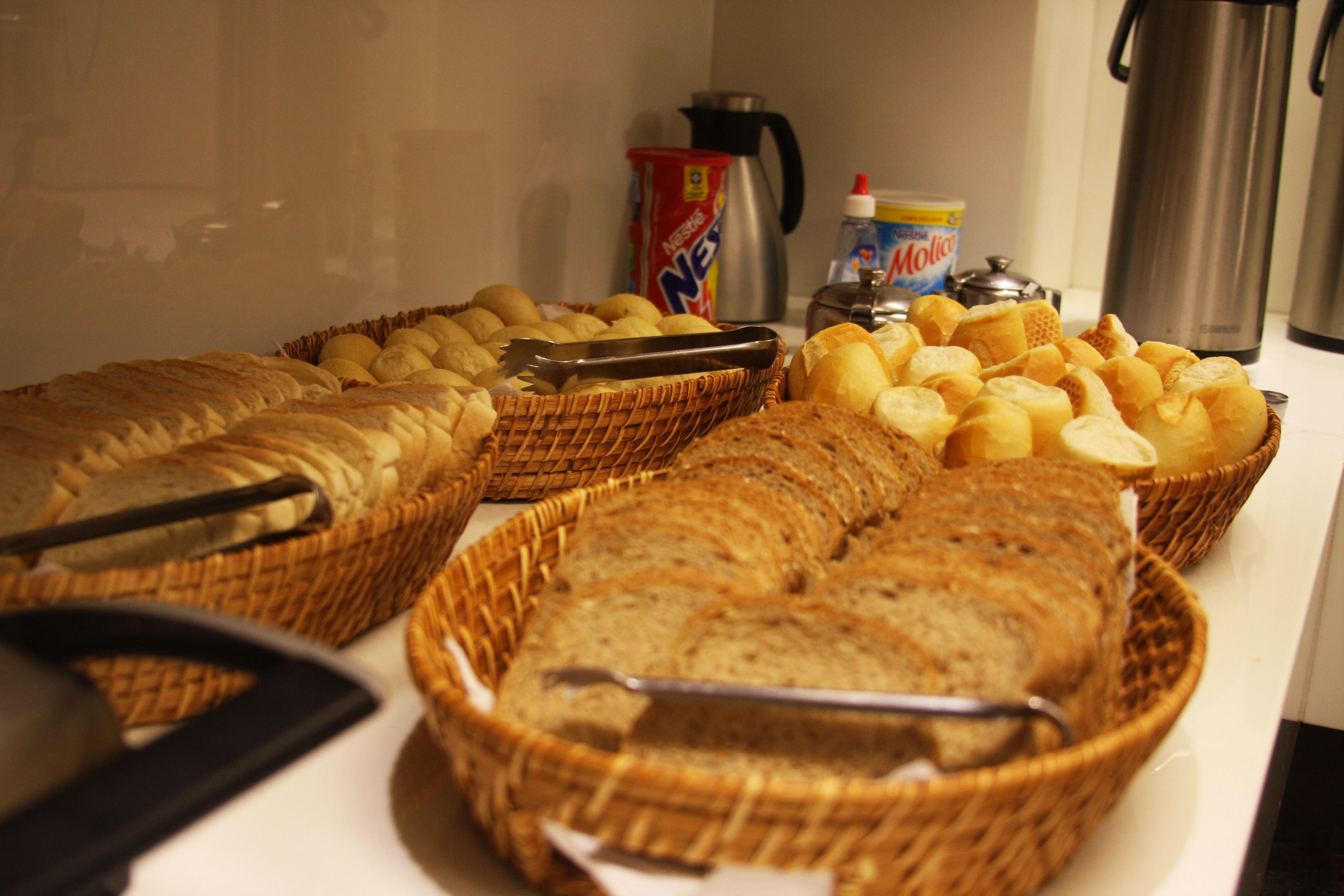 Une table de buffet avec divers pains et pâtisseries présentés dans des paniers en osier.
