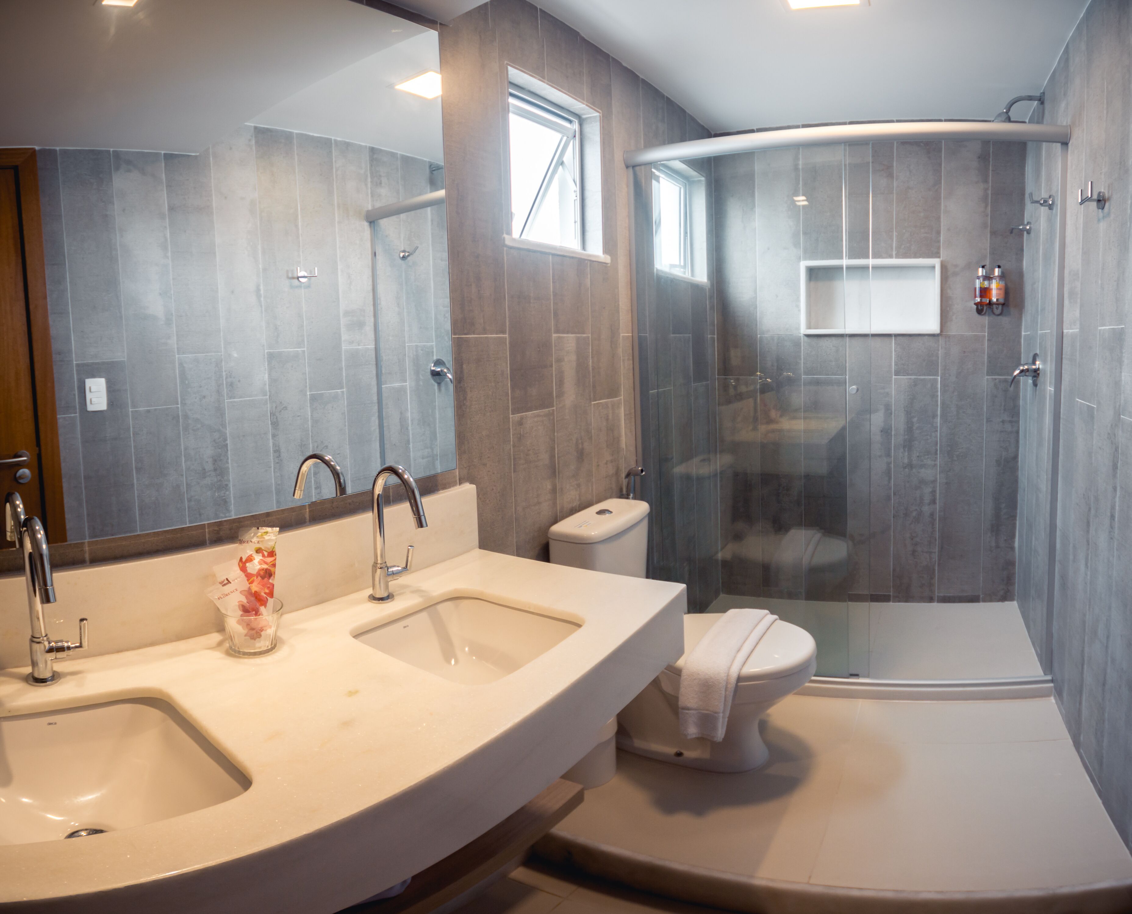 A modern bathroom with two sinks, a toilet, and a glass-enclosed shower.