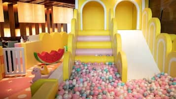 Zona infantil con piscina de pelotas, tobogán y decoración de sandía.