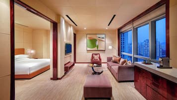 A hotel room with a bed, a sofa, an ottoman, a coffee machine, and a city view.