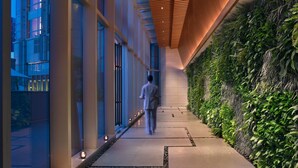 A corridor with a wooden slatted ceiling, glass walls, and a green vertical garden. - Grand Hyatt Shenzhen (Shenzhen)