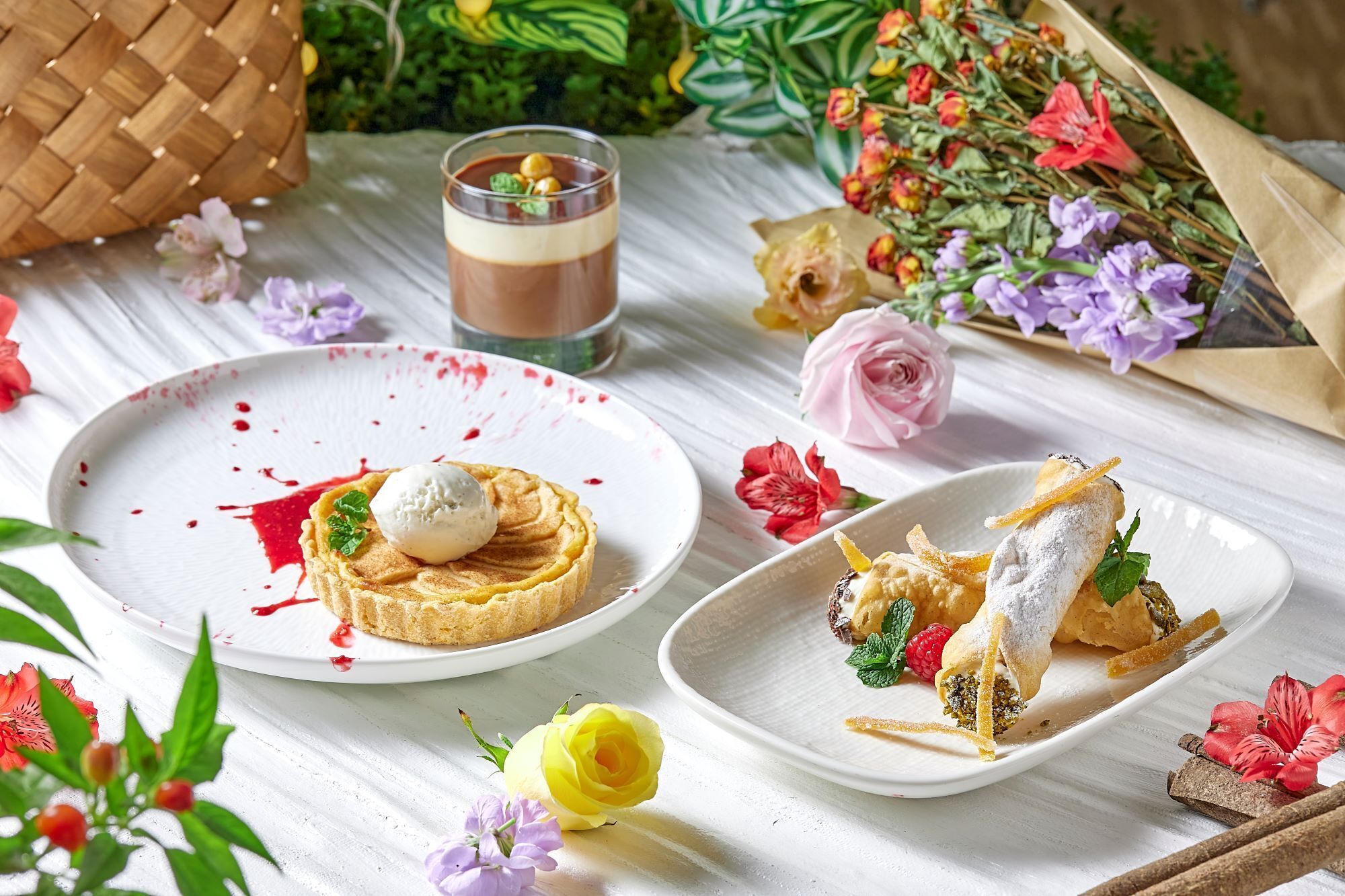 Una mesa con un plato de postre, un vaso de bebida en capas y un plato con un pastel enrollado.