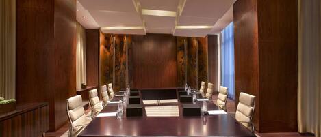 A conference room with a long table, chairs, and a modern ceiling design.