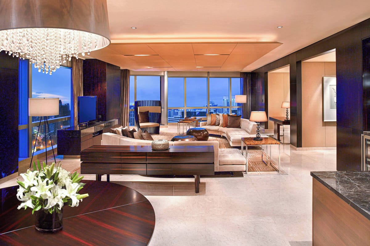 A modern living room with a large window, a sofa, a coffee table, and a chandelier.
