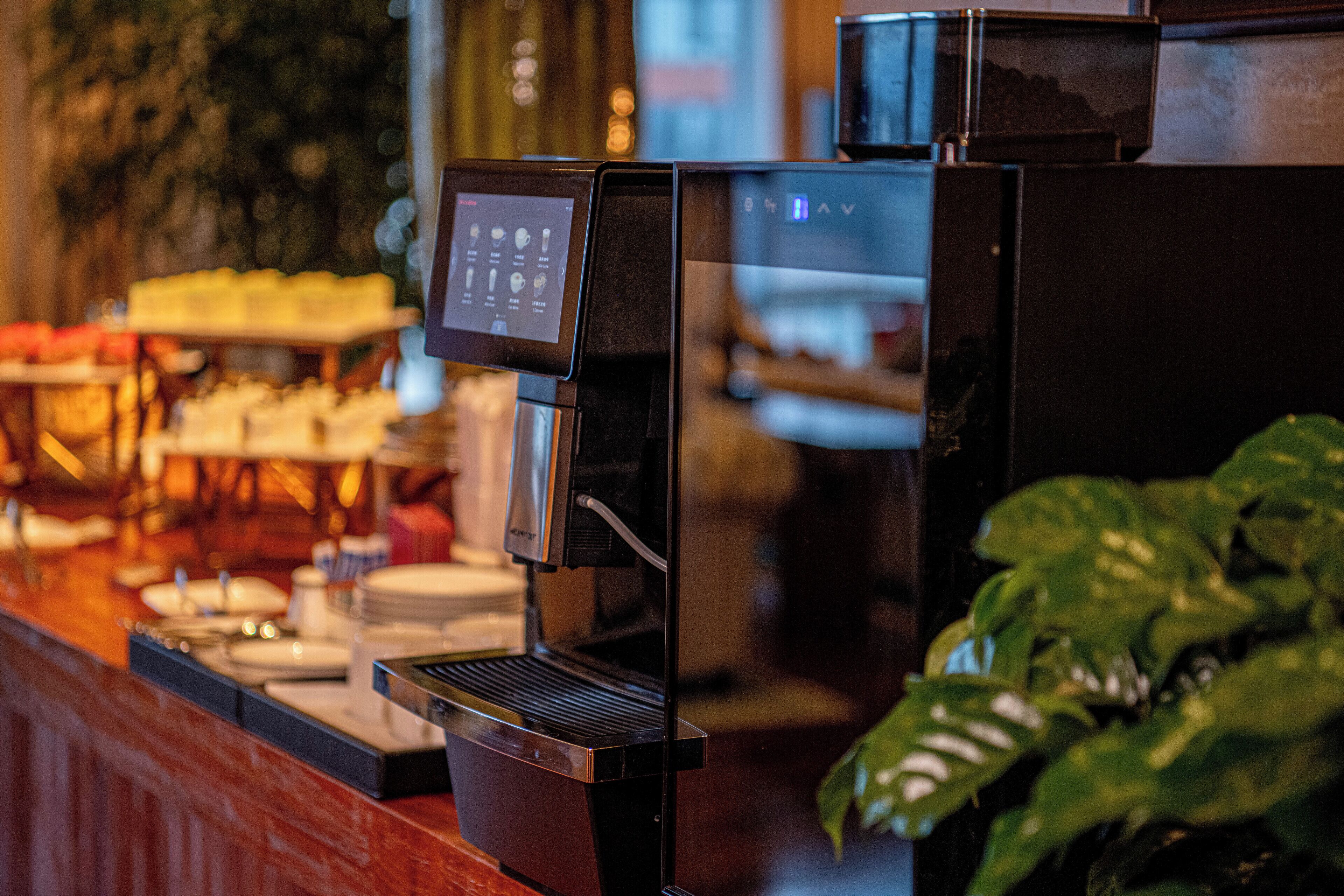 Eine Kaffeemaschine mit digitalem Display, Wasserbehälter und Tropfschale.