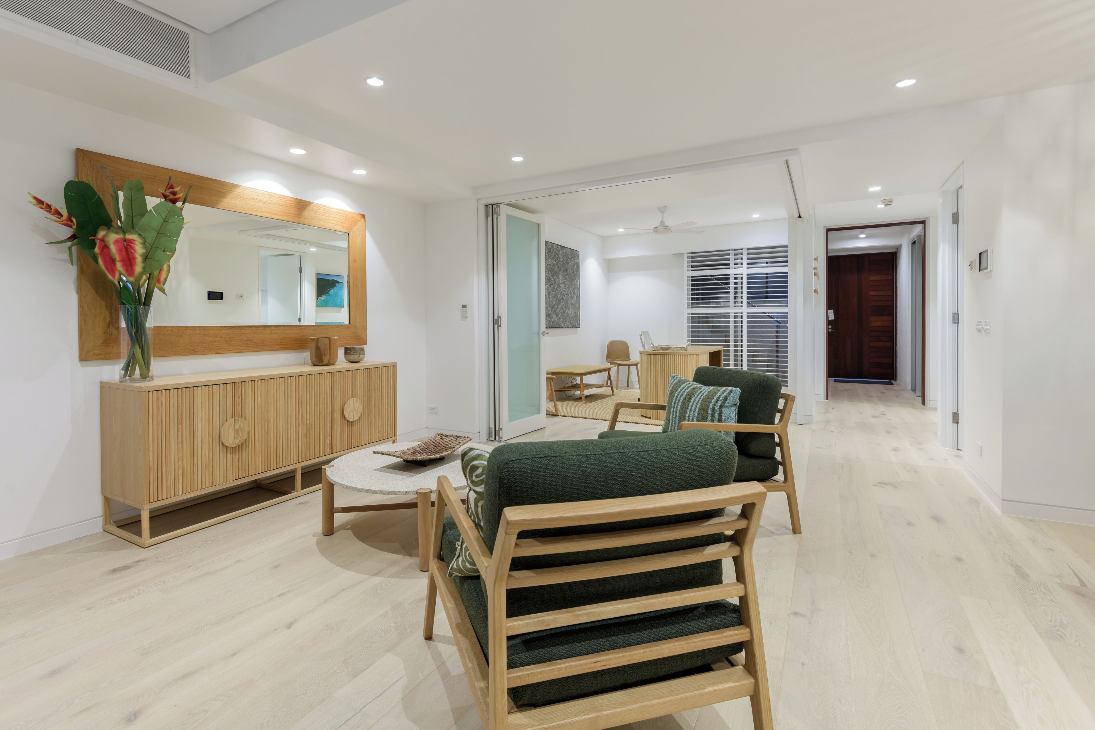 A modern living room with a wooden cabinet, a green sofa, and a dining area with a table and chairs.