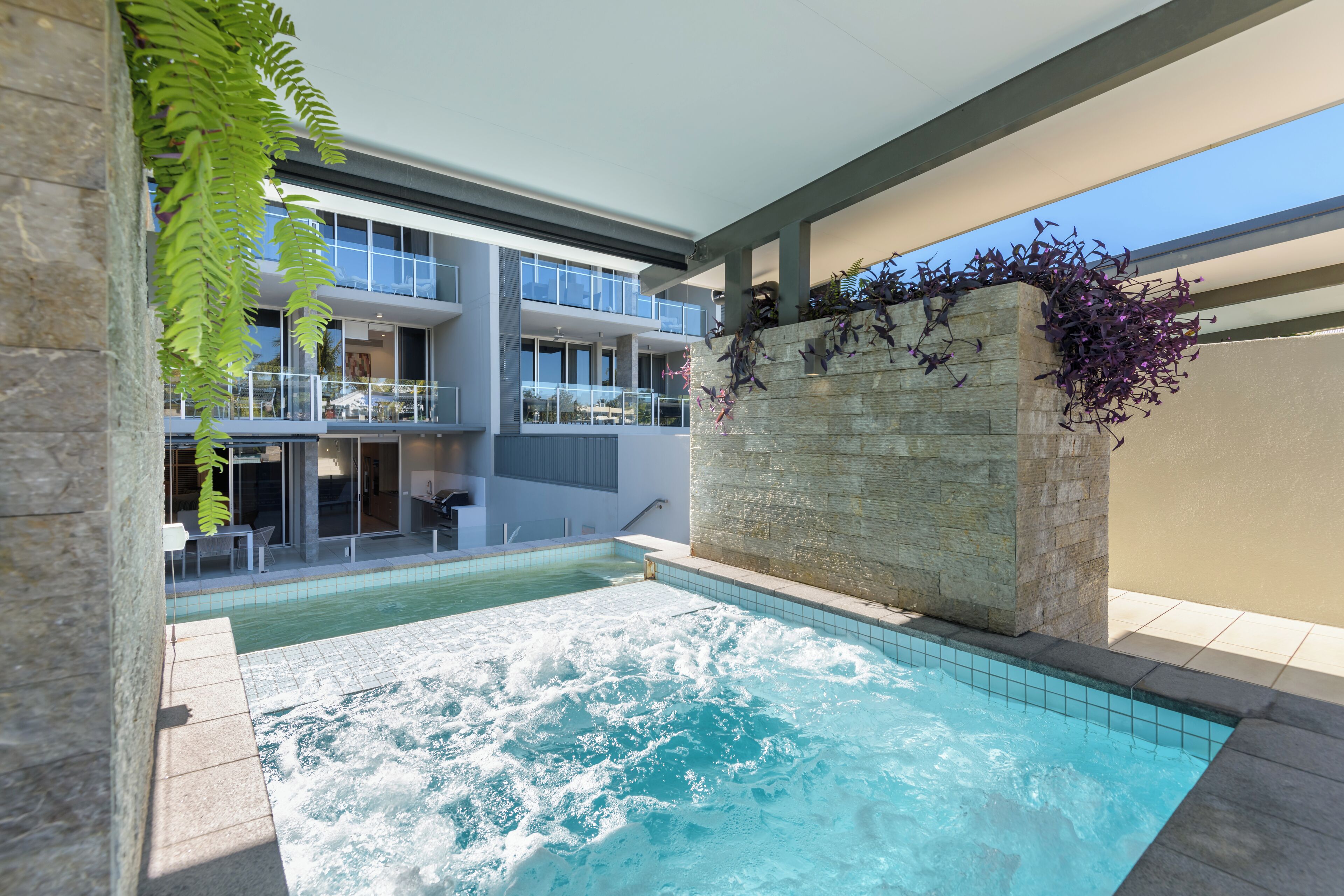 Un hotel moderno con piscina en la azotea, asientos al aire libre y vistas a la ciudad.