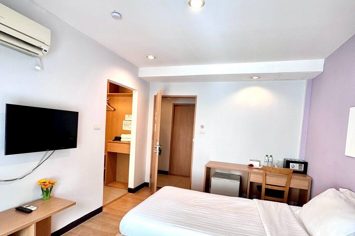 Ein Hotelzimmer mit zwei Betten, einem Schreibtisch mit Stuhl, einem Fernseher und einer Klimaanlage.