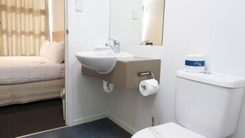 Un baño de hotel con cama, lavamanos, inodoro y espejo.