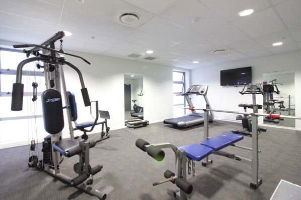 A gym with various exercise equipment, a treadmill, and a bench.