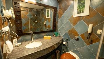A bathroom with a granite countertop, a sink, a mirror, a toilet, and a shower area.