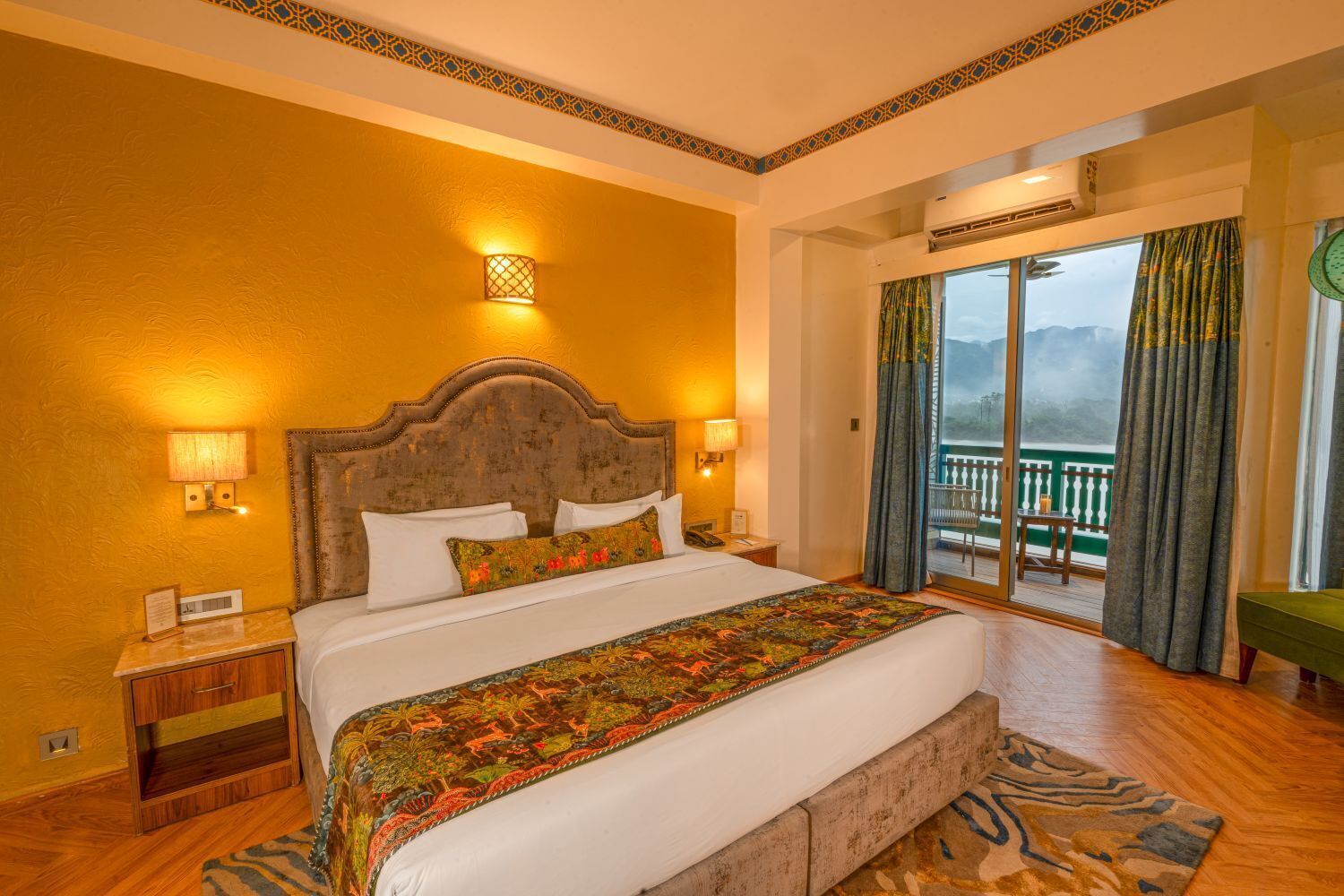 A hotel room with a large bed, a nightstand, a bedside table, a window with curtains, and a view of the outdoors.