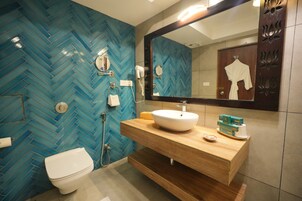 A bathroom with a blue herringbone tile wall, a white toilet, a wooden vanity with a sink, and a large mirror.
