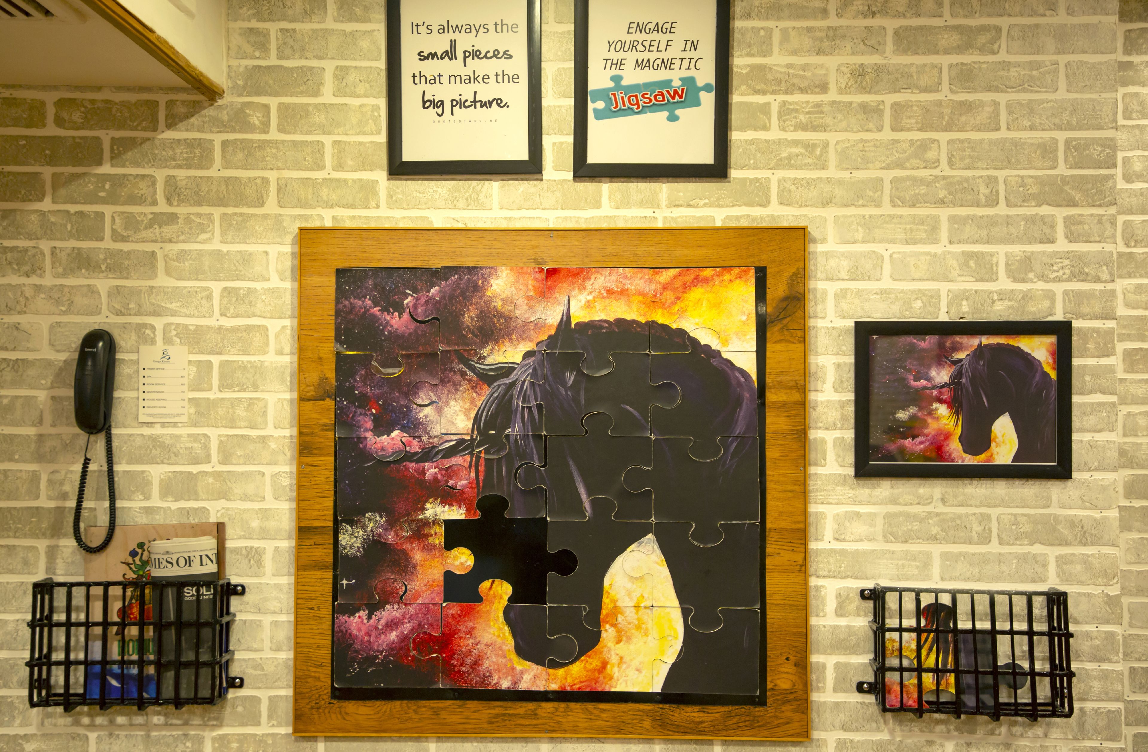 A wall with a large jigsaw puzzle, two framed motivational quotes, and a phone on the left.