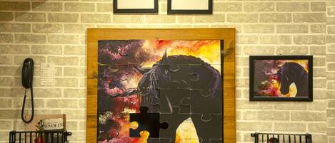 A wall with a large jigsaw puzzle, two framed motivational quotes, and a phone on the left.