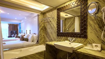 Un baño moderno con lavamanos de mármol, un espejo grande y una zona de ducha.