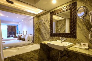 Un baño moderno con lavamanos de mármol, un espejo grande y una zona de ducha.