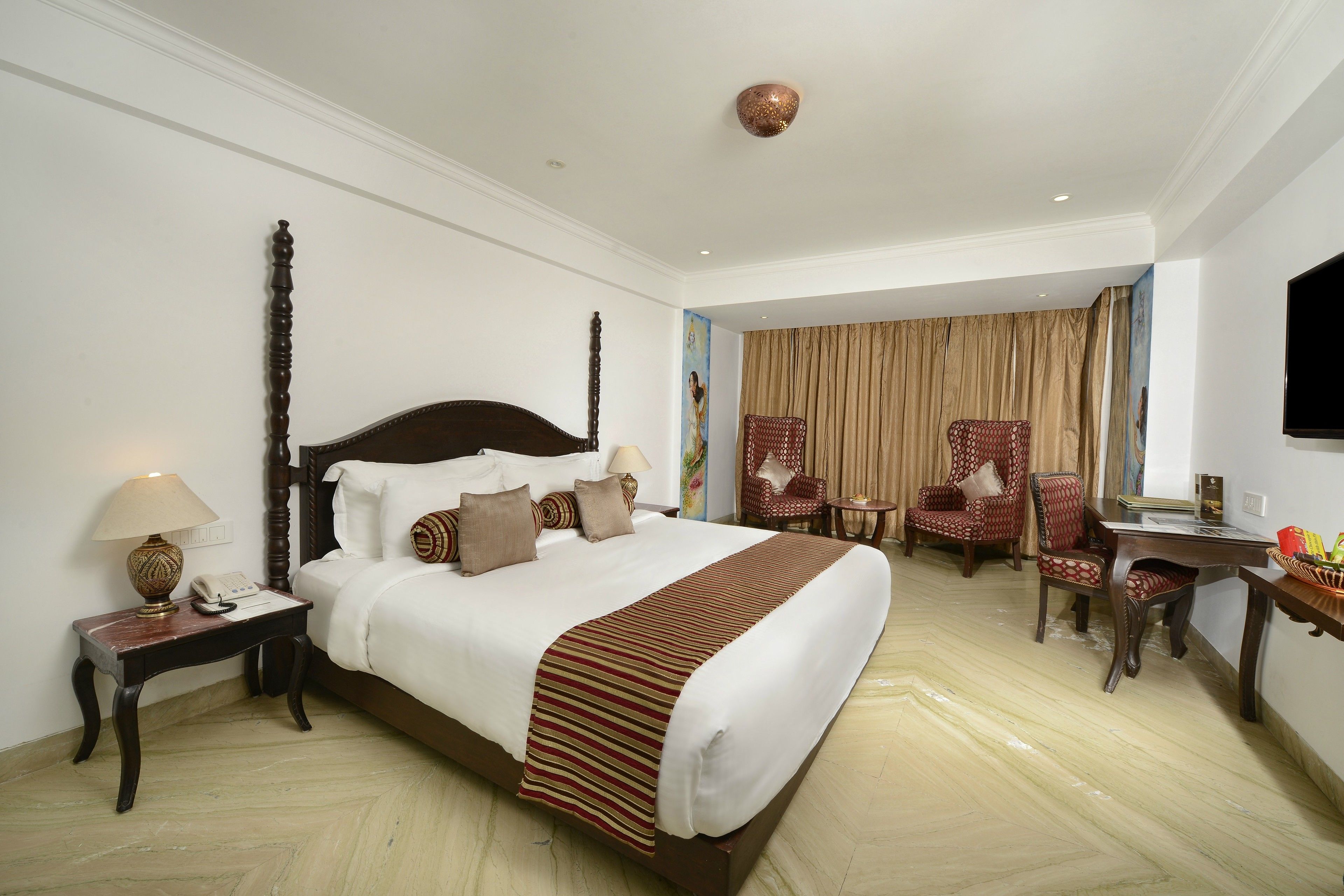 A hotel room with a large bed, a desk, a chair, and a television.