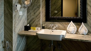 Un baño con pared de mármol, un lavabo con espejo y dispensador de toallas.