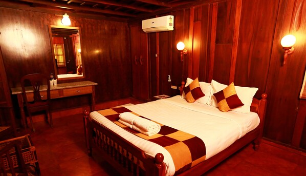 A wooden room with a bed, a desk, and a mirror.
