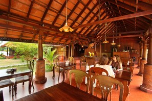 Un restaurante con mobiliario de madera y techo de paja.