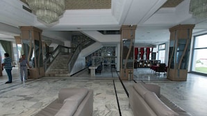 Un hall d’entrée spacieux doté d’un sol en marbre, d’un escalier et d’un coin salon avec des canapés.