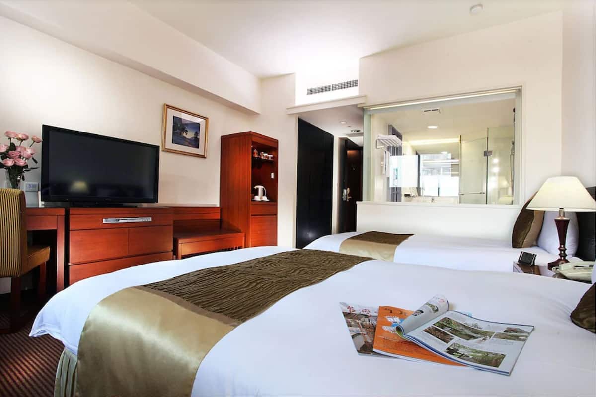 Una habitación de hotel con una cama grande, televisión, escritorio de madera y espejo.