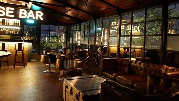 A bar area with a bar counter, seating, and large windows. - Gala Hotel (Taipei)