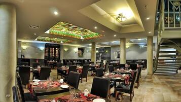 A spacious dining area with multiple tables and chairs, a staircase, and a decorative ceiling light fixture.