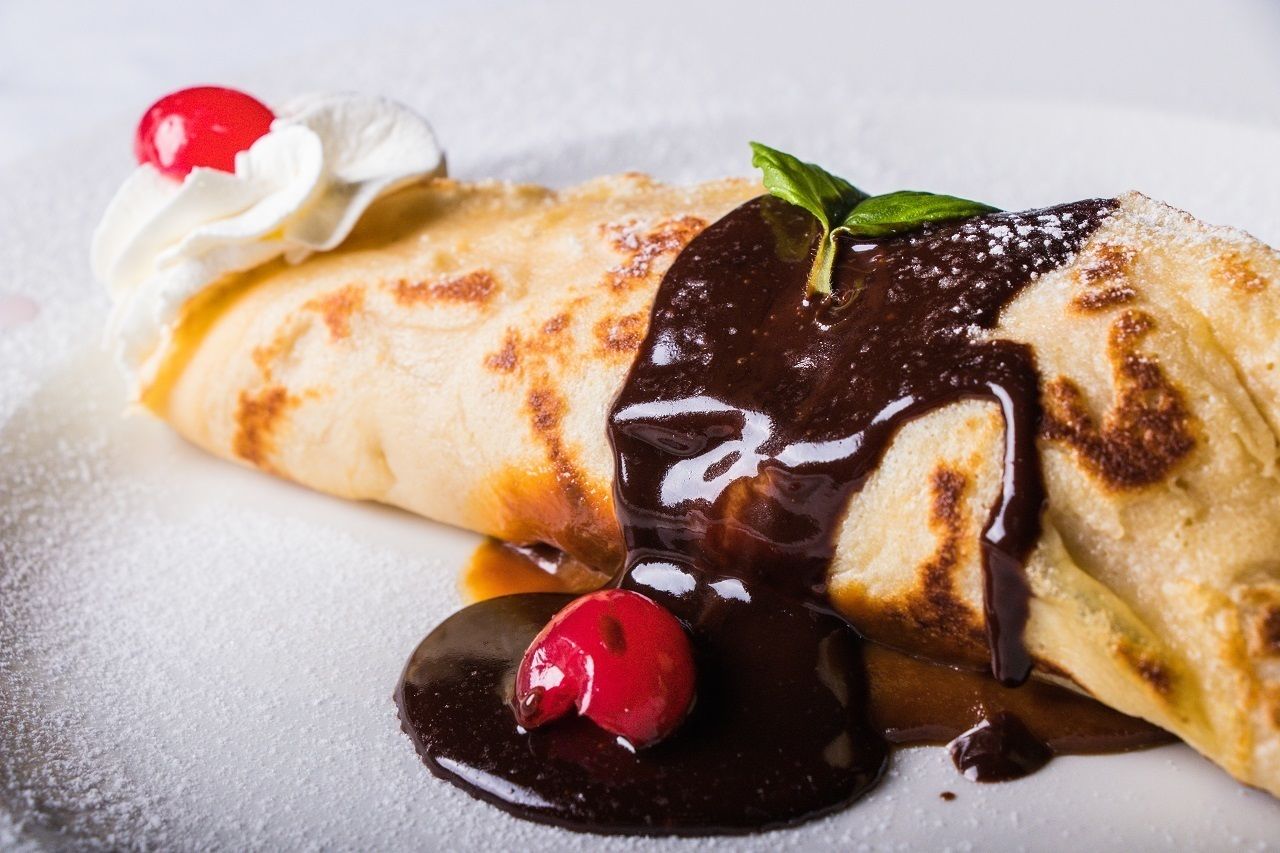 Una crepe con salsa de chocolate y crema batida.