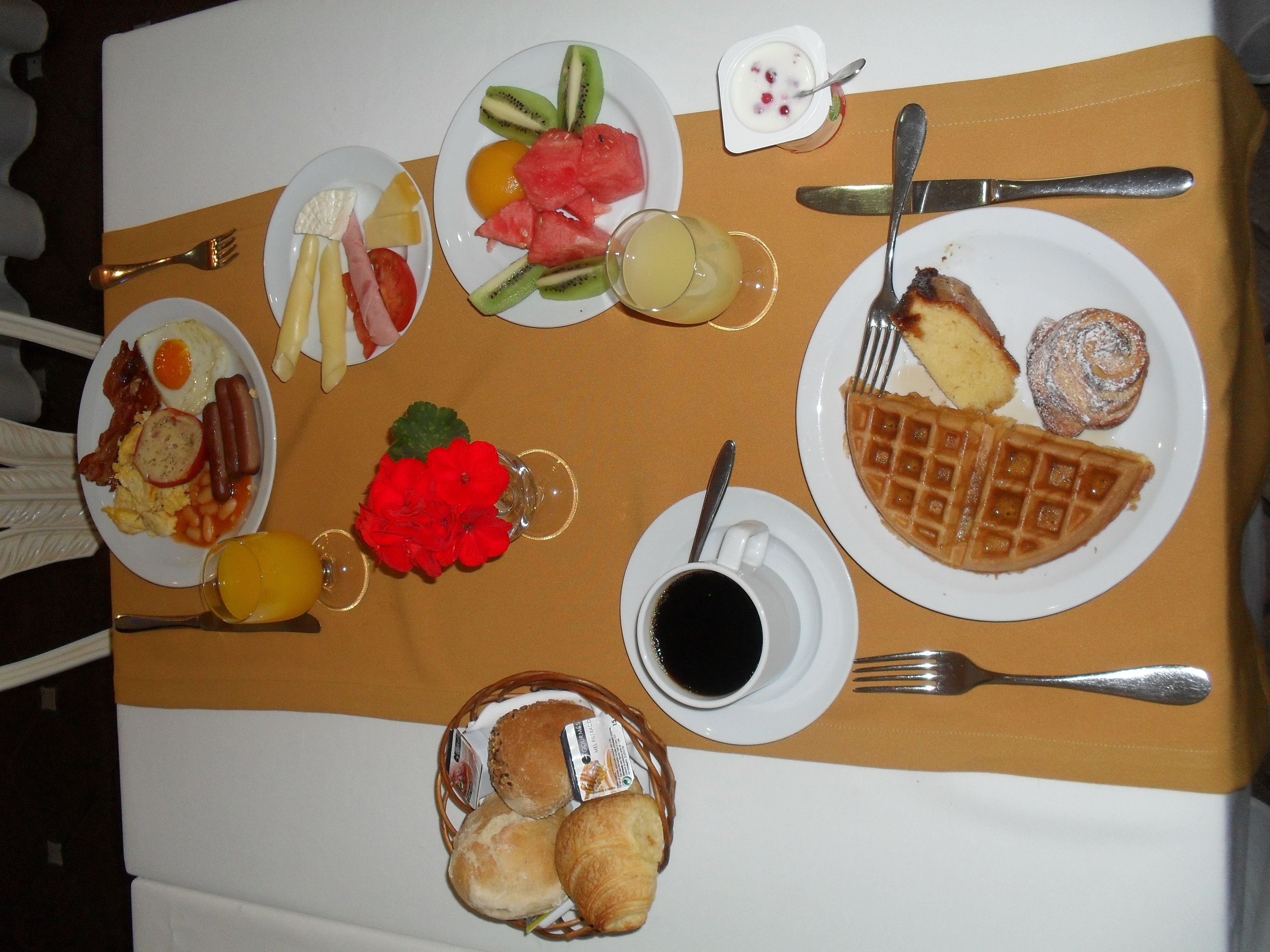 Une table de petit-déjeuner avec divers plats, notamment des œufs, des saucisses et des gaufres.