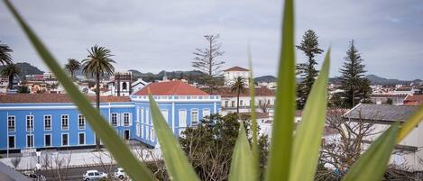 Vista de un pueblo con edificios, incluyendo un edificio azul con ventanas blancas y palmeras.