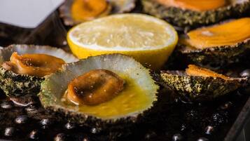 Una bandeja de mariscos a la parrilla, incluyendo ostras y camarones, con cuñas de limón.