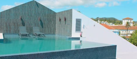 A modern infinity pool with a clear view of the sky and distant buildings.