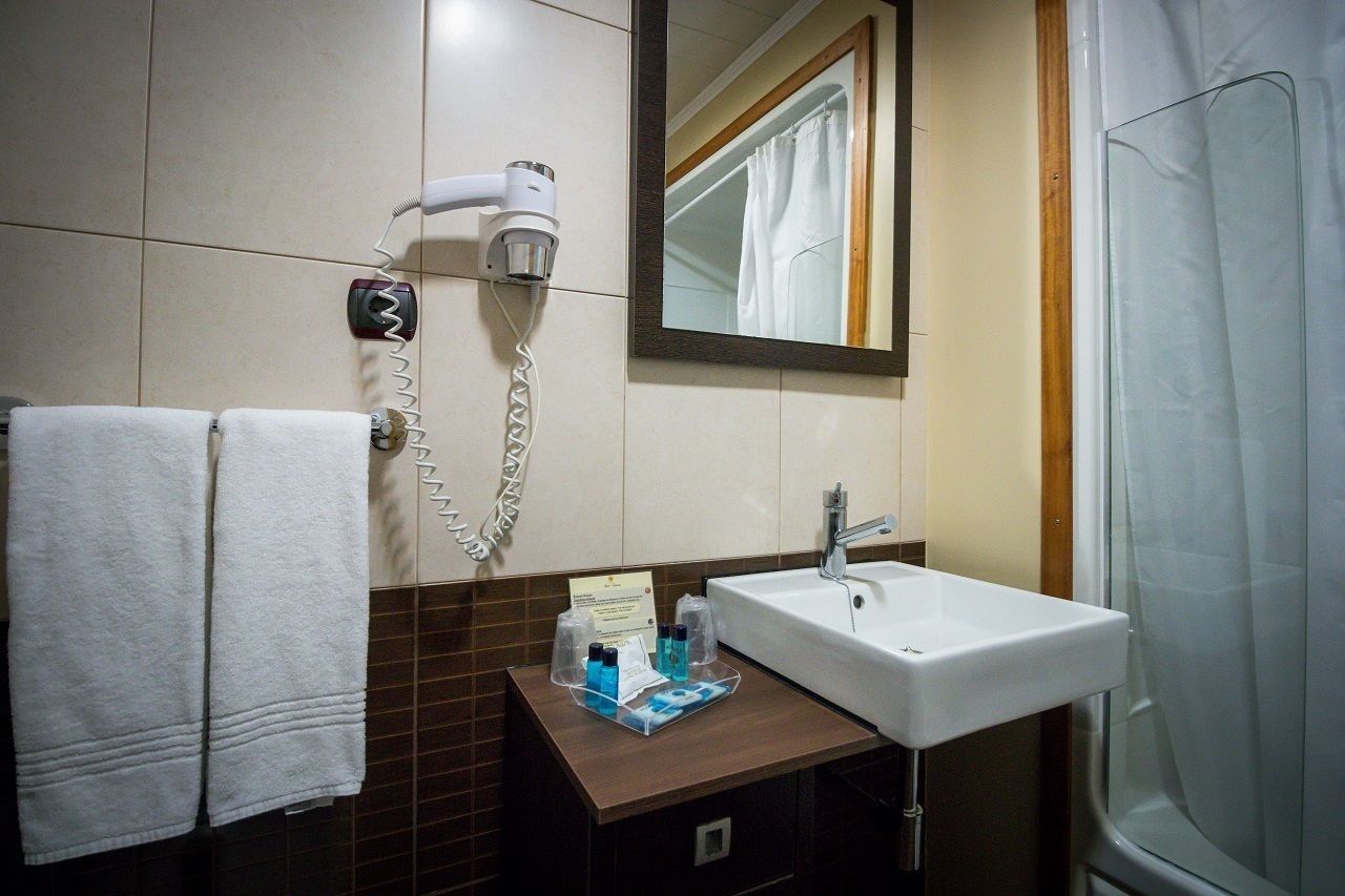 A bathroom with a white sink, a hairdryer, and a mirror.