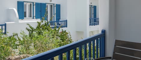 Un balcone con un tavolo rotondo, una sedia e vista su un edificio bianco con persiane blu.