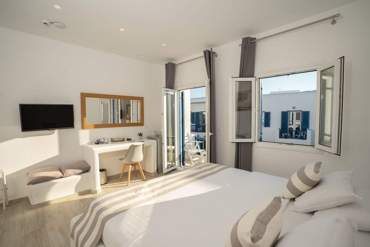 Ein modernes Hotelzimmer mit Bett, Schreibtisch, Stuhl, Fernseher und einem Balkon mit Blick.