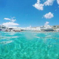 Na praia, espreguiçadeiras, guarda-sóis, toalhas de praia 