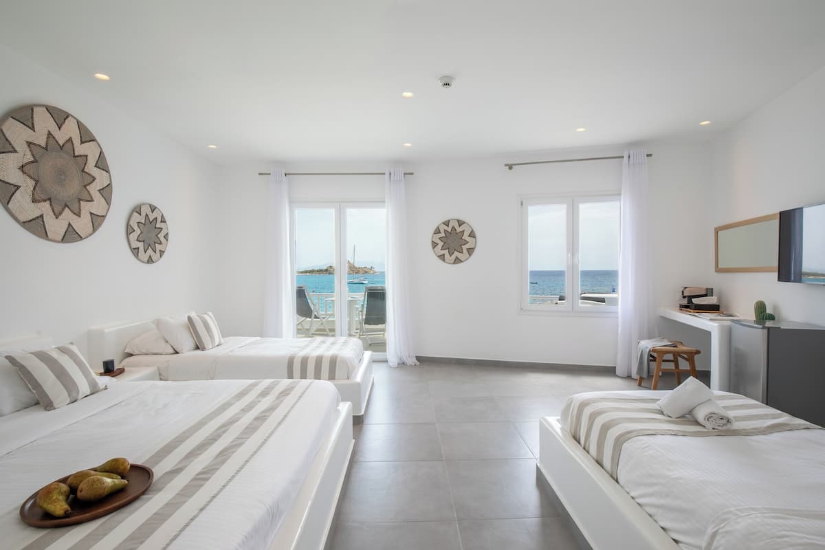 Ein Hotelzimmer mit zwei Betten, einem Schreibtisch und Blick auf das Meer.
