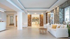 Un vestíbulo amplio con una recepción, un sofá blanco y una pared de acento de piedra.