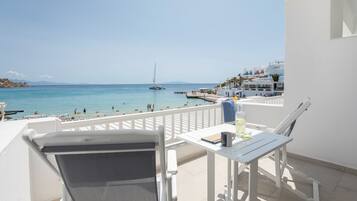 Un balcon avec vue sur la mer, un voilier et des bâtiments blancs.