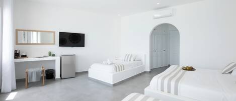 A modern hotel room with a large bed, a smaller bed, a desk, and a TV.