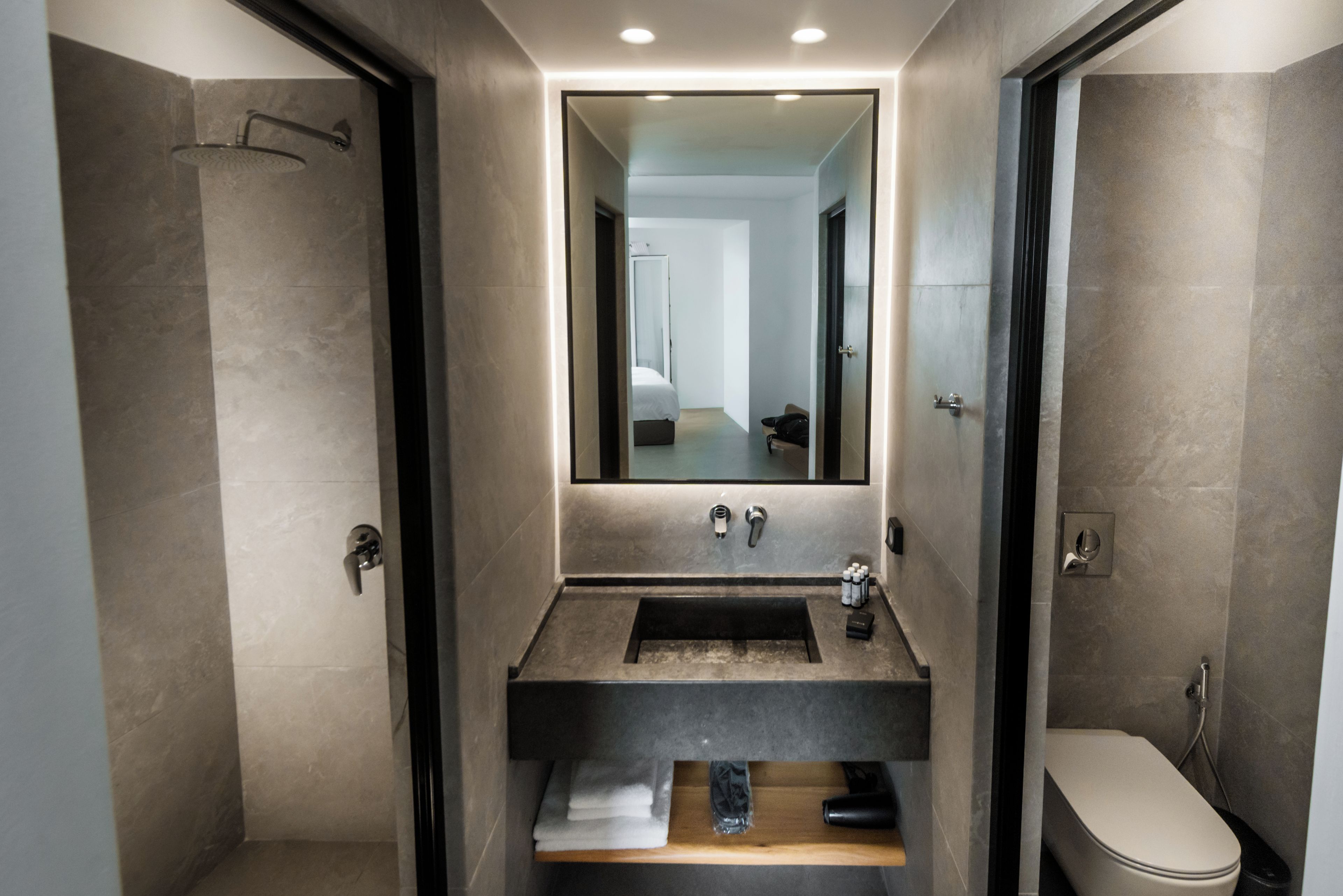 A modern bathroom with a large mirror, a sink, and a toilet.
