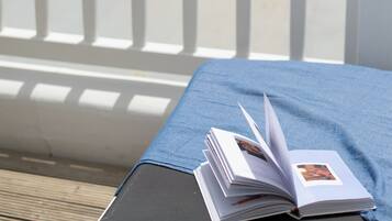 Um livro sobre uma mesa, com vista para o mar e barcos ao fundo.