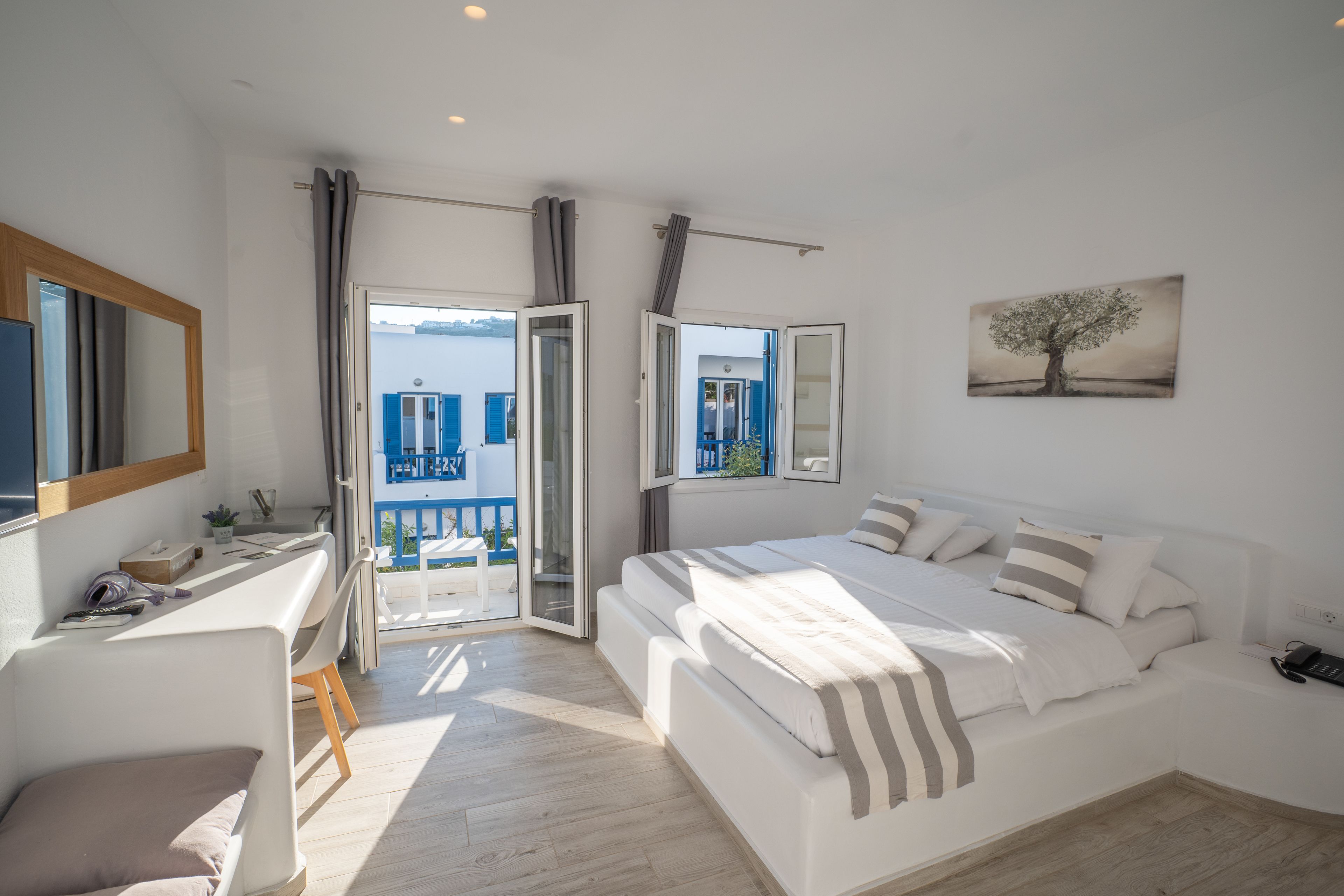 A modern bedroom with a large bed, a desk, and a view of the outside.