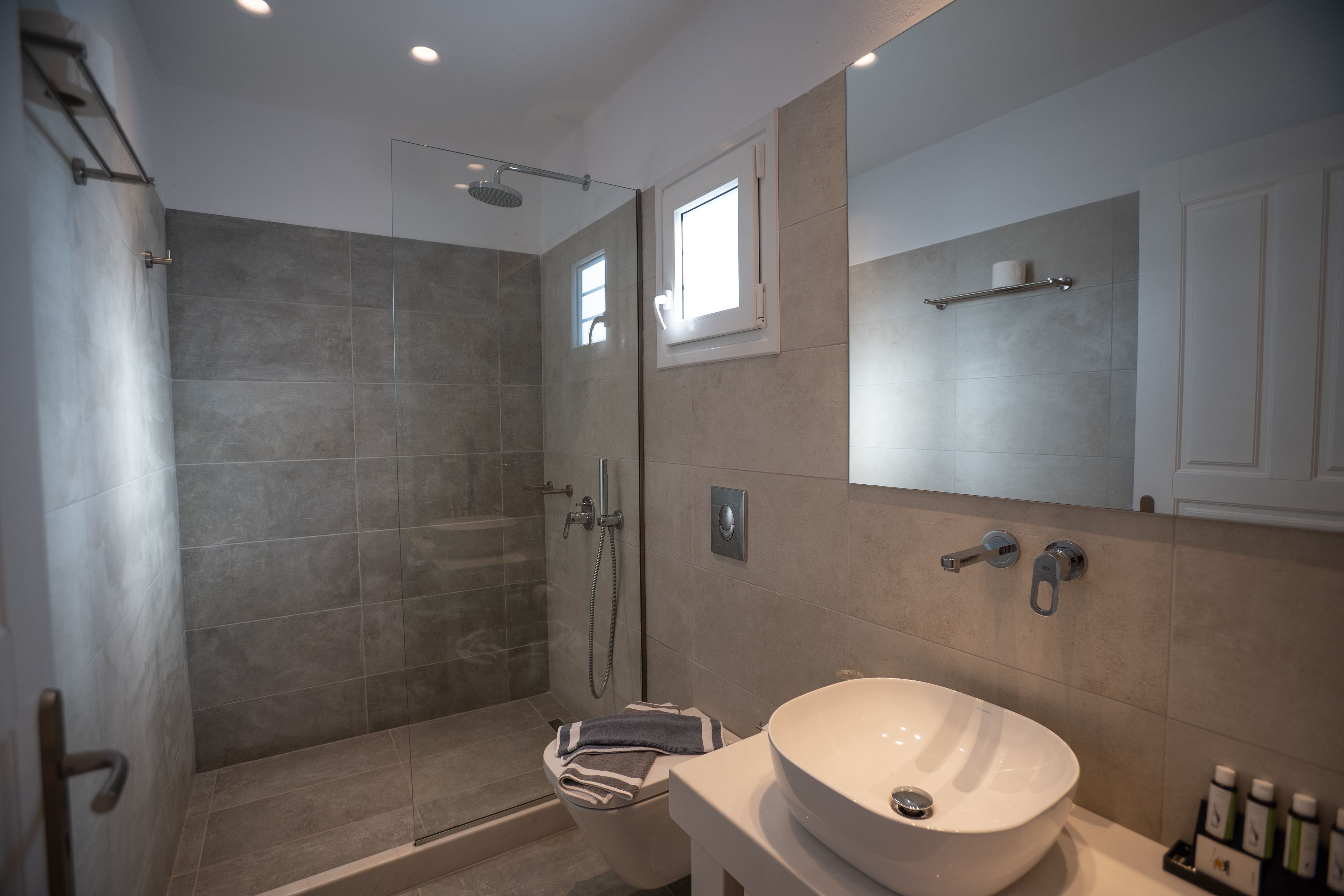 Une salle de bain moderne avec une douche à parois de verre, un grand miroir et un lavabo blanc.