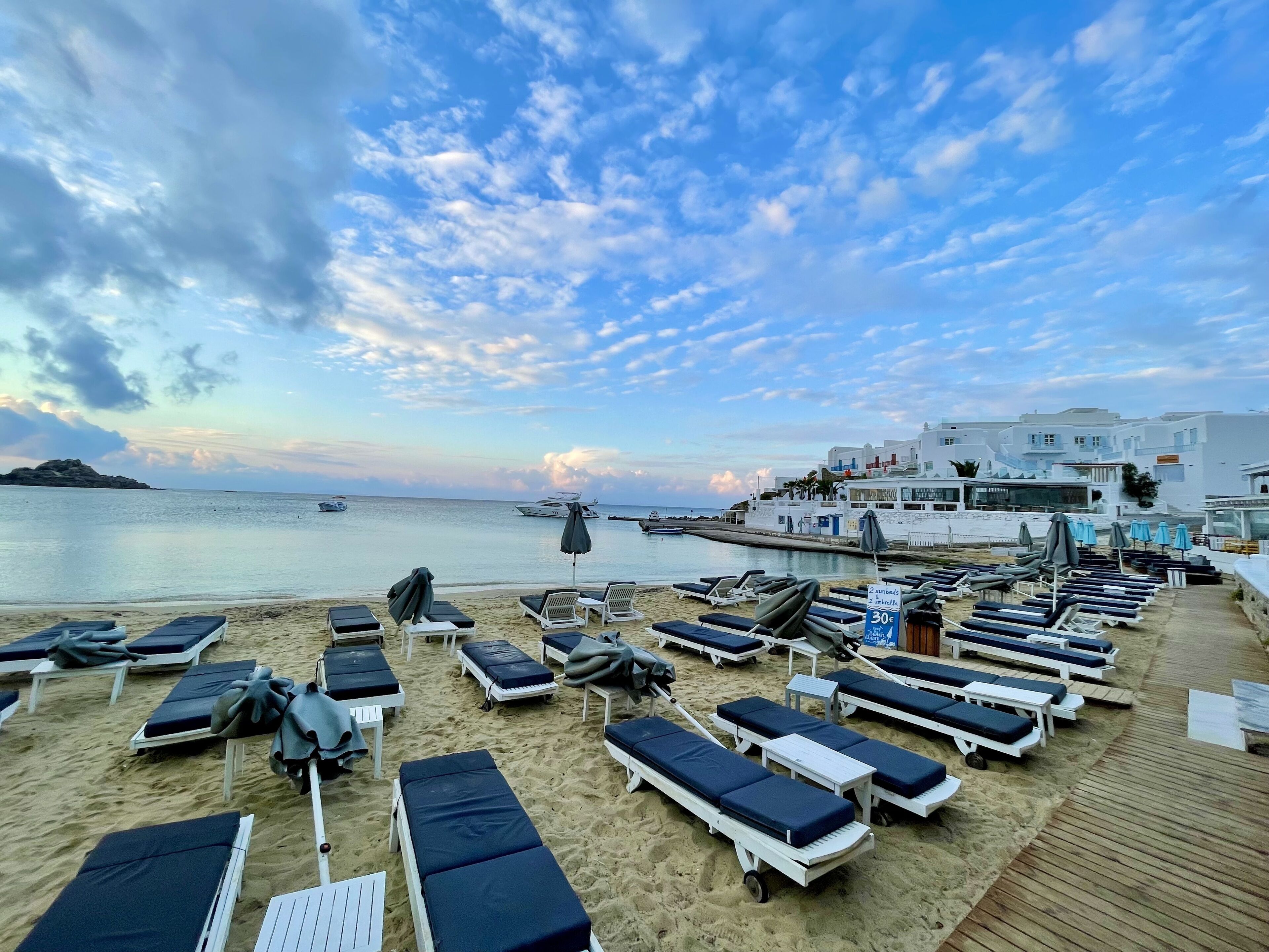 Une plage avec des transats et des parasols, un ciel dégagé et une étendue d’eau.