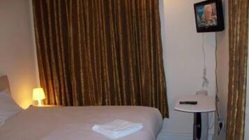 Una habitación de hotel con una cama, una mesita de noche, una lámpara y un cuadro en la pared.